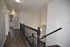 Hallway with dark hardwood / wood-style floors and a chandelier