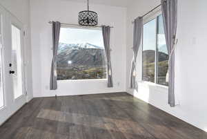 Unfurnished dining area featuring a mountain view, dark hardwood / wood-style floors, and a healthy amount of sunlight