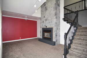 Unfurnished living room featuring a fireplace, carpet, vaulted ceiling, and ornamental molding