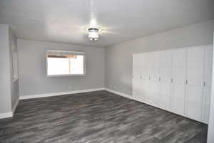 Unfurnished bedroom with a textured ceiling, a closet, and dark wood-type flooring