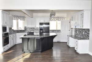 Kitchen featuring white cabinetry, a kitchen island, dark stone counters, and appliances with stainless steel finishes