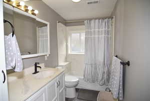 Full bathroom featuring vanity, shower / bath combination with curtain, and toilet