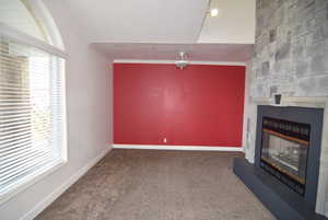 Unfurnished living room with a fireplace, carpet flooring, and crown molding