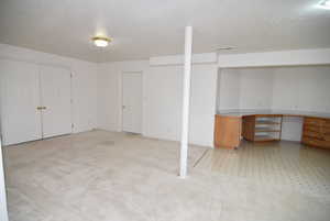 Basement with light carpet and a textured ceiling