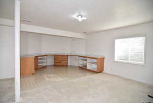 Unfurnished office featuring built in desk and light colored carpet