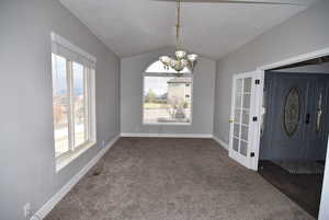 Unfurnished dining area with a chandelier, dark carpet, and vaulted ceiling