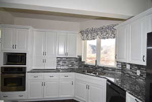 Kitchen with built in microwave, sink, dark stone countertops, oven, and white cabinets