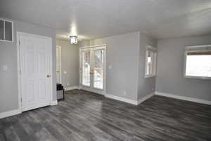 Unfurnished room with dark hardwood / wood-style flooring and a textured ceiling