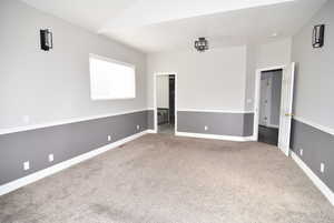 Spare room featuring carpet and lofted ceiling