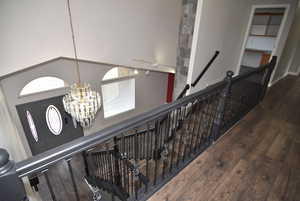 Stairs with hardwood / wood-style floors and a notable chandelier