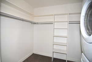 Walk in closet featuring dark carpet and stacked washer / dryer