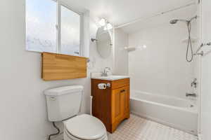 Full bathroom with tile patterned flooring, toilet, vanity, and tiled shower / bath