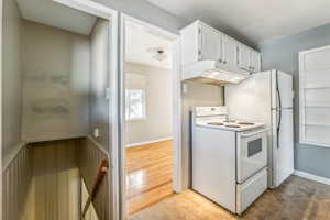 Kitchen with light tile patterned flooring, white cabinets, and white range with electric cooktop