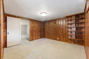 Empty room featuring wooden walls and light carpet