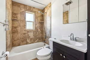 Full bathroom with tiled shower / bath combo, toilet, and vanity