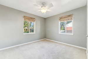 Carpeted spare room featuring ceiling fan