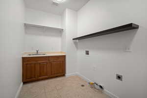 Laundry room with cabinets, hookup for a washing machine, hookup for an electric dryer, light tile patterned floors, and sink