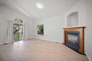 Unfurnished living room with hardwood / wood-style flooring, a fireplace, and high vaulted ceiling