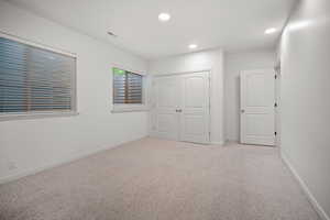 Unfurnished bedroom featuring light carpet and a closet