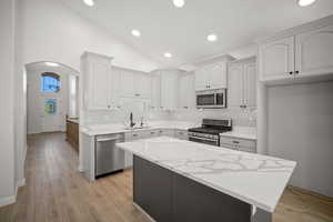 Kitchen featuring sink, tasteful backsplash, light hardwood / wood-style flooring, and appliances with stainless steel finishes