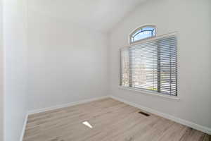 Unfurnished room with vaulted ceiling and light hardwood / wood-style flooring