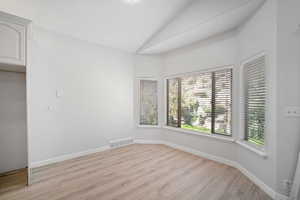 Spare room featuring light hardwood / wood-style floors and lofted ceiling