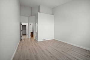 Unfurnished bedroom with a high ceiling and light hardwood / wood-style flooring