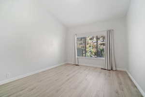 Spare room with vaulted ceiling and light hardwood / wood-style flooring