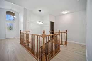 Hallway featuring an inviting chandelier, light hardwood / wood-style floors, and lofted ceiling