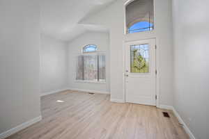 Entryway with vaulted ceiling and light hardwood / wood-style floors