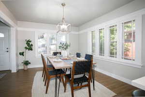 Dining area with dark hardwood / wood-style flooring and a notable chandelier