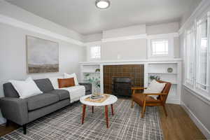 Living room with plenty of natural light, a wood stove, wood-type flooring, and a tile fireplace