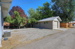 Exterior space featuring a garage, cooling unit, and an outdoor structure