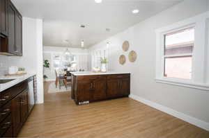 Kitchen with kitchen peninsula, light hardwood / wood-style flooring, backsplash, and dark brown cabinets