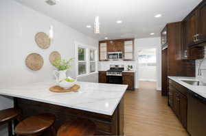 Kitchen featuring light wood-type flooring, backsplash, appliances with stainless steel finishes, and plenty of natural light