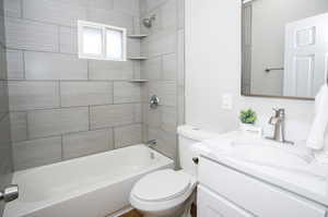 Full bathroom featuring toilet, tiled shower / bath combo, and vanity