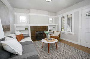 Living room with a fireplace, plenty of natural light, and wood-type flooring