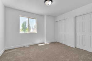 Unfurnished bedroom featuring new carpet and multiple closets