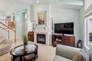 Living room featuring a wealth of natural light, a fireplace, high vaulted ceiling, and light colored carpet