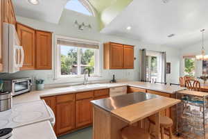 Kitchen with sink, plenty of natural light, an inviting chandelier, and white appliances