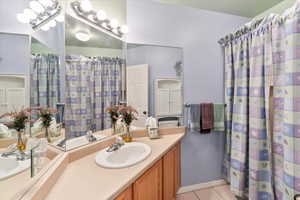 Bathroom featuring tile patterned flooring, vanity, and a chandelier