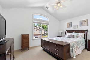 Carpeted bedroom featuring ceiling fan and vaulted ceiling