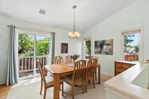 Dining area with light wood-type flooring, vaulted ceiling, and a notable chandelier