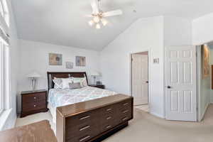 Bedroom featuring ceiling fan, multiple windows, vaulted ceiling, and light carpet