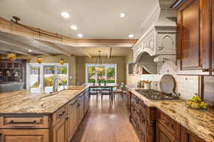 Kitchen with hardwood / wood-style floors, backsplash, sink, beam ceiling, and pendant lighting