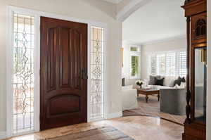 Entryway with light marble patterned floors and ornamental molding