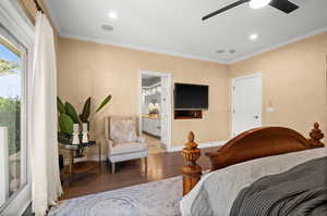 Bedroom featuring hardwood / wood-style flooring, ornamental molding, ensuite bath, and ceiling fan