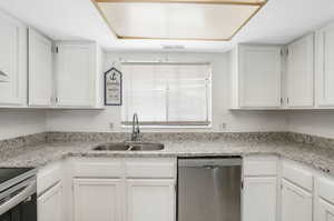 Kitchen with sink, dishwasher, white cabinetry, and a wealth of natural light