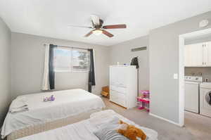 Carpeted bedroom featuring ceiling fan and washing machine and clothes dryer