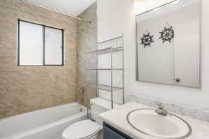 Full bathroom with tiled shower / bath, vanity, and toilet